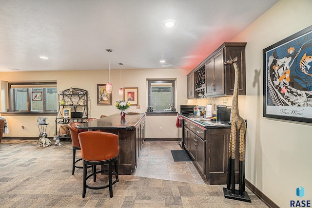 kitchen with dark brown cabinets, a breakfast bar, a kitchen island, and decorative light fixtures