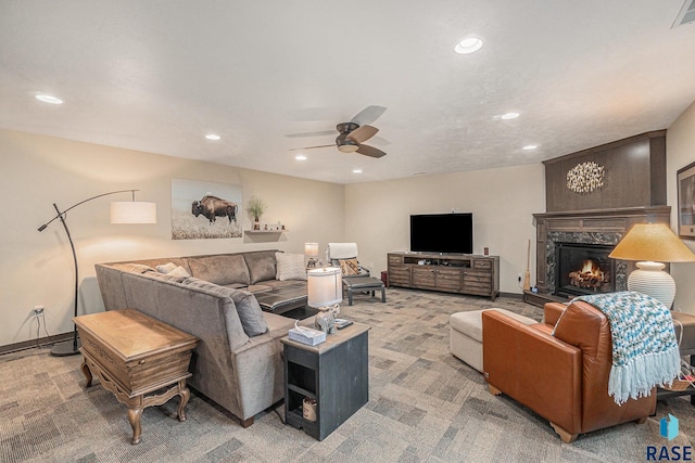 living room featuring a high end fireplace, carpet floors, and ceiling fan