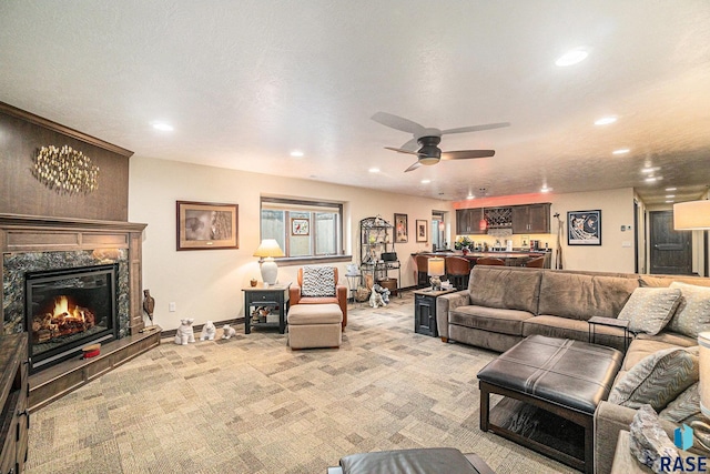 living room with ceiling fan, bar area, a textured ceiling, light carpet, and a fireplace