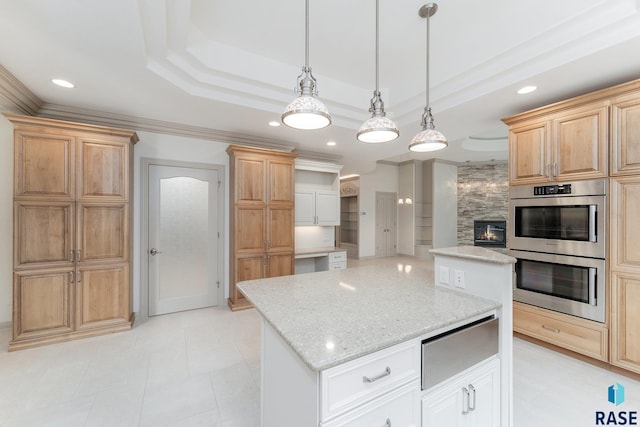 kitchen featuring pendant lighting, a kitchen island, double oven, and a tiled fireplace