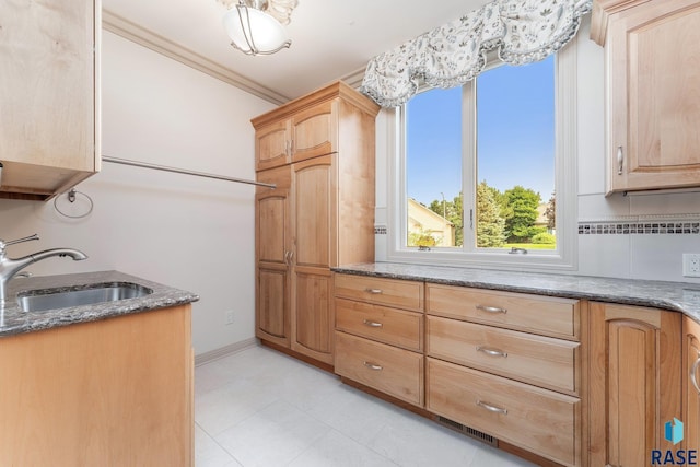 kitchen with sink, decorative backsplash, dark stone countertops, ornamental molding, and light brown cabinetry