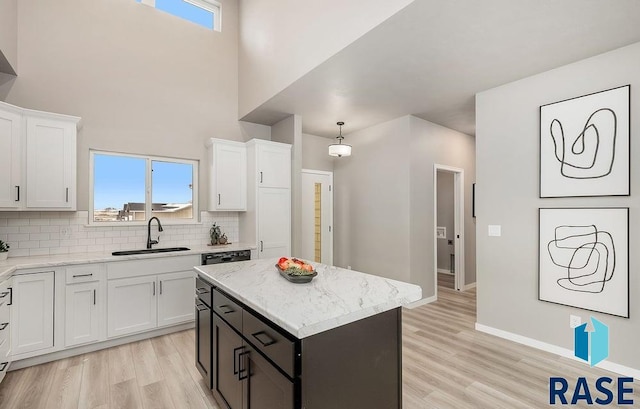 kitchen with sink, light hardwood / wood-style flooring, a center island, white cabinetry, and hanging light fixtures