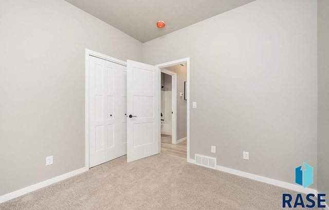 unfurnished bedroom featuring light colored carpet and a closet