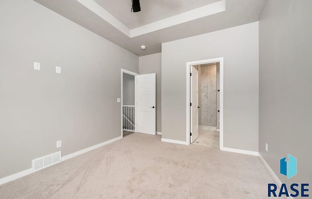 unfurnished bedroom featuring ceiling fan, light colored carpet, and connected bathroom