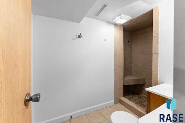 bathroom featuring tile patterned floors, toilet, vanity, and tiled shower