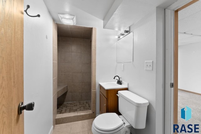 bathroom featuring a tile shower, vanity, tile patterned flooring, toilet, and lofted ceiling