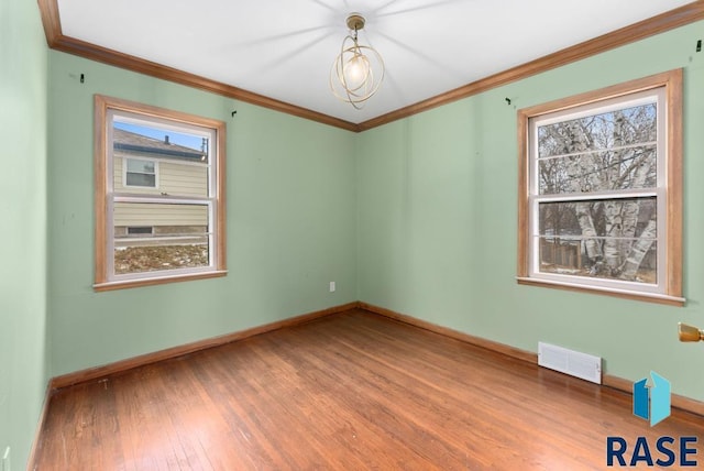 spare room with ornamental molding, a healthy amount of sunlight, and hardwood / wood-style flooring