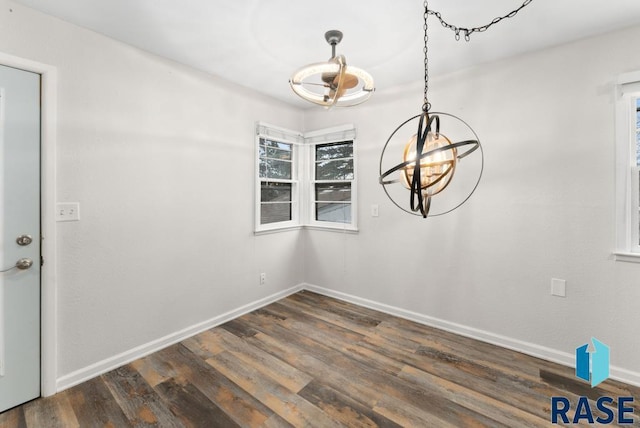 unfurnished dining area with dark hardwood / wood-style floors and an inviting chandelier