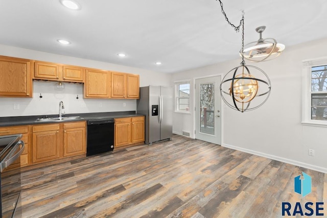 kitchen featuring pendant lighting, sink, appliances with stainless steel finishes, dark hardwood / wood-style flooring, and a chandelier