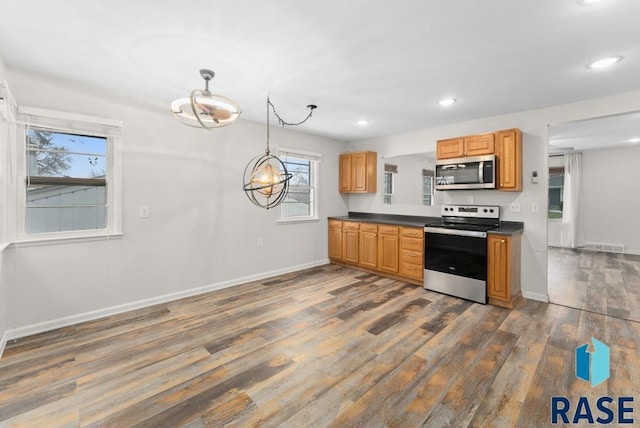 kitchen with stainless steel appliances, hanging light fixtures, and dark wood-type flooring