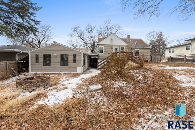 snow covered house with a fire pit and a deck