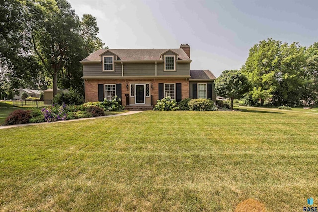 view of front of home featuring a front yard, brick siding, and a chimney