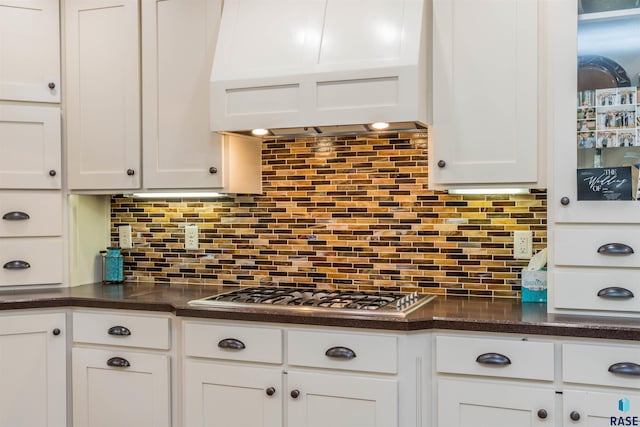 kitchen with white cabinets, custom exhaust hood, stainless steel gas cooktop, and tasteful backsplash