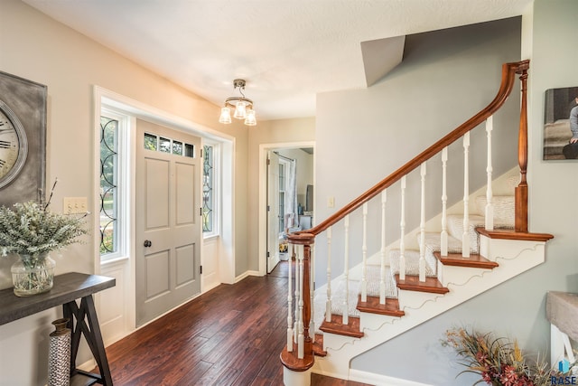 foyer entrance featuring dark wood-type flooring and an inviting chandelier