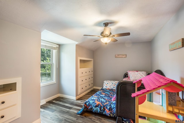 bedroom with a textured ceiling, vaulted ceiling, ceiling fan, and dark wood-type flooring