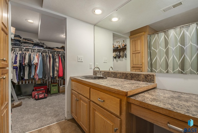 bathroom with tile patterned flooring, vanity, and a textured ceiling