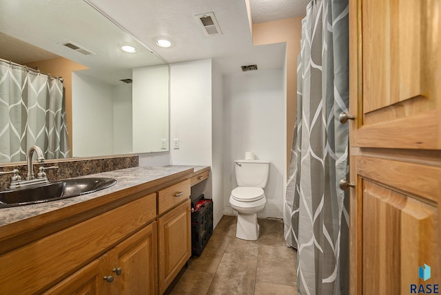 bathroom with tile patterned flooring, a textured ceiling, vanity, and toilet