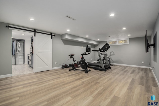 exercise area featuring light hardwood / wood-style floors and a barn door