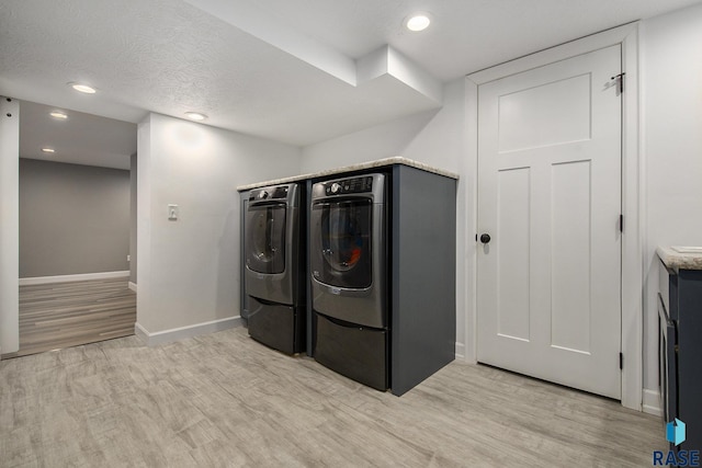 laundry room featuring light hardwood / wood-style flooring, a textured ceiling, and independent washer and dryer