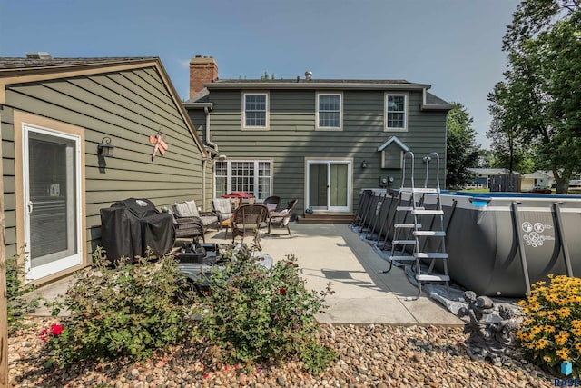 rear view of property with a fenced in pool and a patio