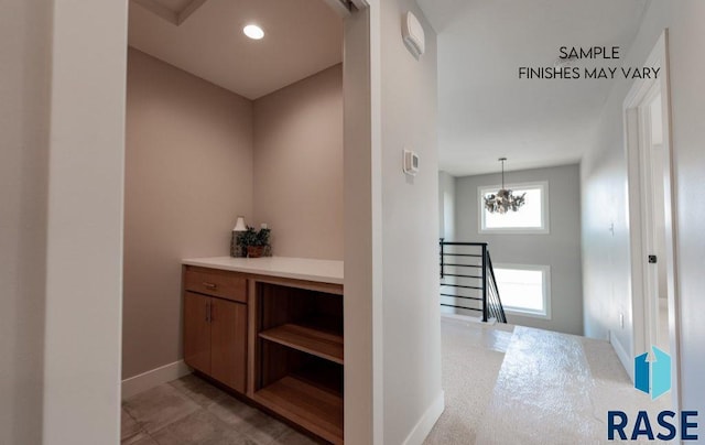 hallway with light tile patterned flooring and an inviting chandelier