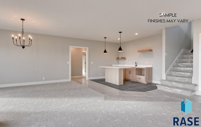 kitchen featuring sink, a center island, dark colored carpet, pendant lighting, and a chandelier