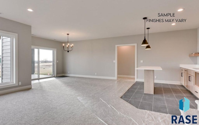 kitchen featuring a breakfast bar area, hanging light fixtures, dark carpet, and a notable chandelier