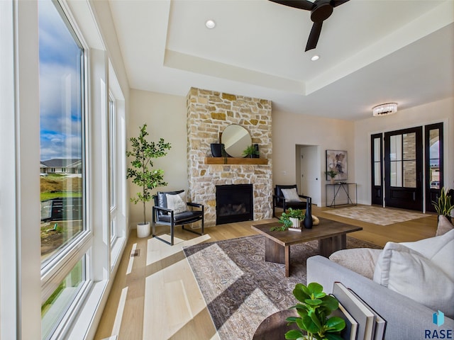 6609 E Hawker Cir, Sioux Falls, SD 57110 - living area with a tray ceiling, a stone fireplace, ceiling fan, and wood finished floors