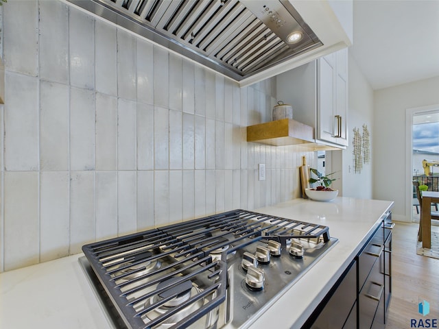 6609 E Hawker Cir, Sioux Falls, SD 57110 - kitchen featuring stainless steel gas cooktop, light wood-style flooring, custom exhaust hood, light countertops, and decorative backsplash