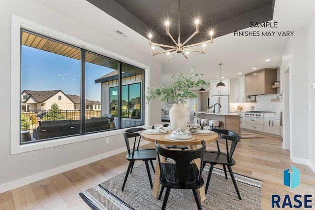 dining room featuring light wood-type flooring, an inviting chandelier, visible vents, and baseboards