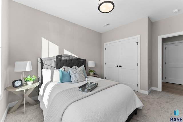 bedroom featuring light carpet, baseboards, visible vents, and a closet