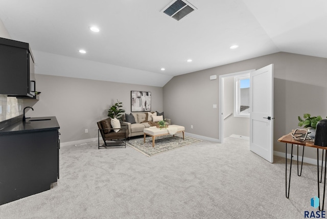 living area with lofted ceiling, light carpet, visible vents, and baseboards