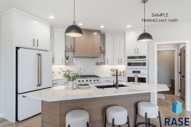 kitchen featuring white appliances, decorative backsplash, a breakfast bar, light wood-type flooring, and a sink