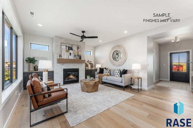 living room with a stone fireplace, wood finished floors, visible vents, and recessed lighting