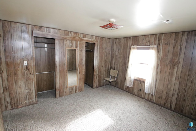 unfurnished bedroom featuring carpet, a closet, and wood walls