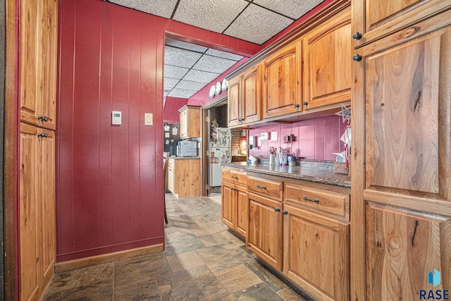 kitchen featuring wooden walls and a drop ceiling