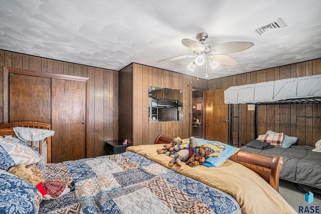 carpeted bedroom with a closet, ceiling fan, and wooden walls