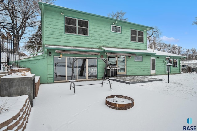 snow covered back of property with a fire pit