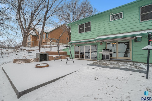 snow covered back of property with a jacuzzi