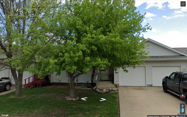 view of property hidden behind natural elements featuring a garage and a front lawn