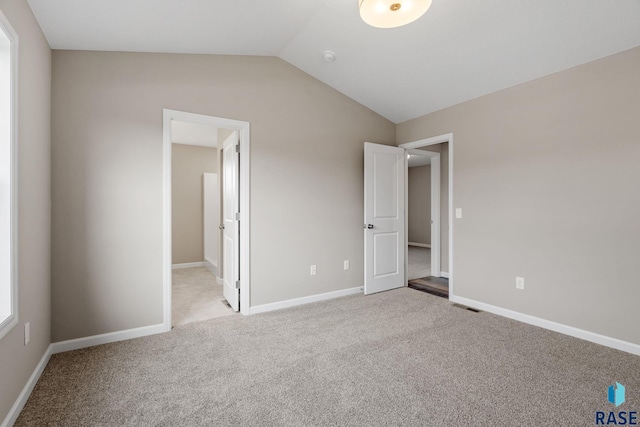 unfurnished bedroom featuring light carpet and vaulted ceiling