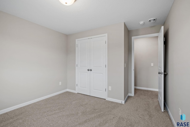 unfurnished bedroom with a closet and light colored carpet