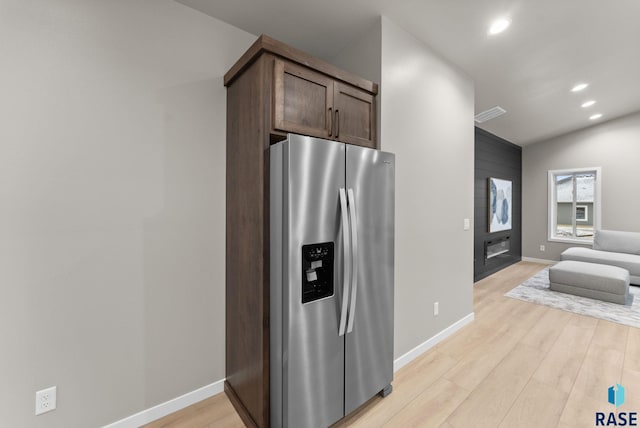 kitchen with stainless steel refrigerator with ice dispenser, dark brown cabinetry, light hardwood / wood-style flooring, and lofted ceiling