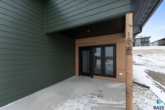 snow covered property entrance featuring french doors