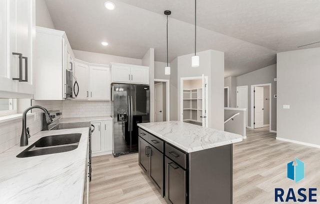 kitchen featuring tasteful backsplash, a kitchen island, sink, stainless steel fridge with ice dispenser, and white cabinetry