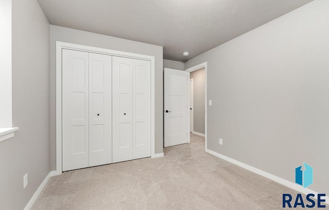 unfurnished bedroom featuring a closet and light colored carpet