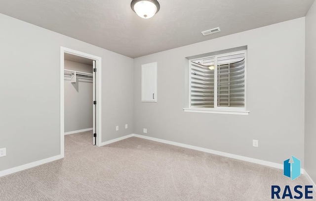 unfurnished bedroom with a spacious closet, light carpet, and a closet