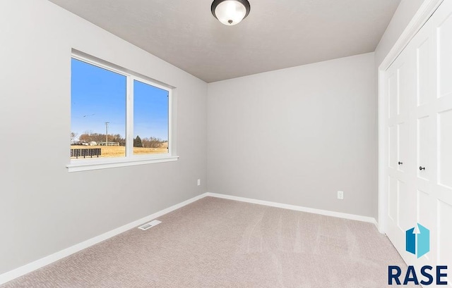 unfurnished bedroom featuring light colored carpet and a closet