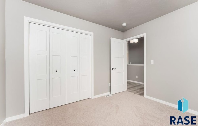 unfurnished bedroom with light carpet and a closet