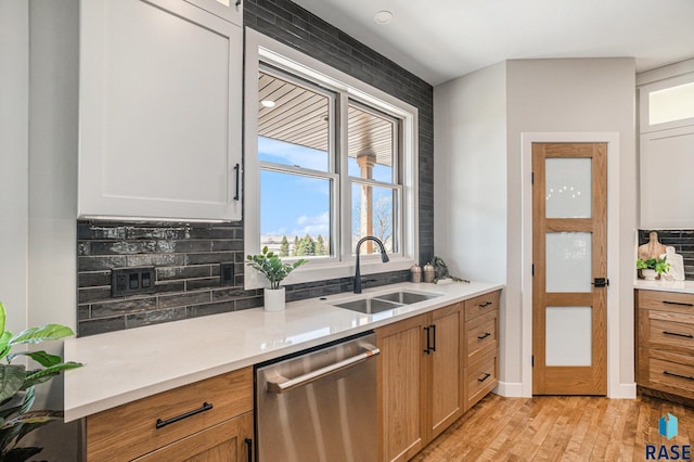 kitchen featuring dishwasher, white cabinets, sink, light hardwood / wood-style flooring, and tasteful backsplash